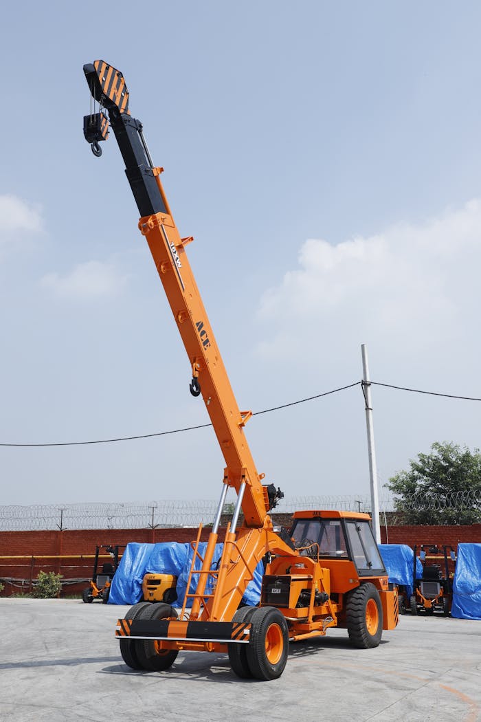 ACE orange hydraulic mobile crane parked outdoors under clear sky, ideal for construction projects.